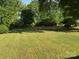 Expansive backyard featuring mature trees, a swing set, and two red storage buildings at 8616 Fallsdale Dr, Charlotte, NC 28214