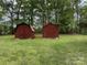 Backyard featuring two red wooden storage sheds on a lush lawn at 8616 Fallsdale Dr, Charlotte, NC 28214