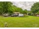 Large grassy backyard with mature trees, utility vehicles, and a trailer on property at 1005 Fieldstone Rd, Mooresville, NC 28115