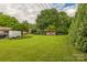 Expansive grassy backyard, mature trees, utility vehicles, trailer, and outbuilding on property at 1005 Fieldstone Rd, Mooresville, NC 28115