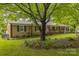 Inviting brick home with green shutters, beautiful landscaping, and a mature shade tree at 1005 Fieldstone Rd, Mooresville, NC 28115