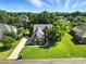 Aerial view of a brick home with a long driveway, surrounded by green lawns and mature trees in a serene setting at 104 Fairwind Ct, Fort Mill, SC 29708