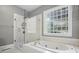 Relaxing primary bath with a glass shower, soaking tub, and unique glass block window at 104 Fairwind Ct, Fort Mill, SC 29708