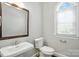 Neutral powder room featuring a pedestal sink, toilet, and arched window for natural lighting at 104 Fairwind Ct, Fort Mill, SC 29708