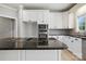 Kitchen island with black granite countertops, smooth cooktop, and stylish white cabinetry at 104 Fairwind Ct, Fort Mill, SC 29708