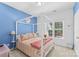 Stylish bedroom with a four-poster bed, bright blue wall, and a sunny window at 122 Laurel Glen Dr, Mooresville, NC 28115