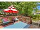 Outdoor wooden deck with blue furniture, patterned rug and red patio umbrella at 122 Laurel Glen Dr, Mooresville, NC 28115
