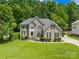 Stately two-story brick home featuring lush lawn, landscaped yard, and mature trees under a sunny sky at 122 Laurel Glen Dr, Mooresville, NC 28115