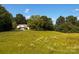 View of a grassy field with trees and a house in the distance on a sunny day at 1243 Cox Mill Rd, Concord, NC 28027