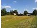 Expansive field with scattered trees and buildings in the distance under a blue sky at 1243 Cox Mill Rd, Concord, NC 28027