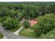 An aerial view showcases a charming home with a red roof, surrounded by lush greenery and mature trees at 1614 Linwood Rd, Gaston, NC 28052