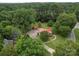 An aerial view showcases a charming home with a red roof, surrounded by lush greenery and mature trees at 1614 Linwood Rd, Gaston, NC 28052