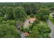 An aerial view showcases a charming home with a red roof, surrounded by lush greenery and mature trees at 1614 Linwood Rd, Gaston, NC 28052