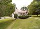 Charming white brick home with a vibrant red roof, lush landscaping and inviting front porch at 1614 Linwood Rd, Gaston, NC 28052