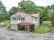 White brick home featuring a red metal roof, wooden steps, covered patio and side greenhouse at 1614 Linwood Rd, Gaston, NC 28052