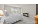 Bedroom features neutral carpet, white bedding, accent pillows, natural light, and bright walls at 2419 Quail Lake Dr, Charlotte, NC 28210