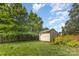 Backyard with a storage shed, a variety of plants, a wooden fence, and mature trees at 2627 Willis Dr, Harrisburg, NC 28075