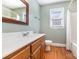 Bathroom features a wooden vanity, faucet, mirror, and a combination tub and shower at 2627 Willis Dr, Harrisburg, NC 28075