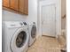 Convenient laundry room featuring modern washer and dryer units, storage cabinets, and tiled flooring at 2627 Willis Dr, Harrisburg, NC 28075