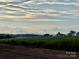 Long view of farmland separated by white fences underneath cloudy blue skies at 3000 Paul Payne Store Rd, Taylorsville, NC 28681
