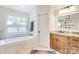 Bright bathroom with a soaking tub, a wooden vanity, and lots of natural light at 3237 Sunset Dr, Charlotte, NC 28209
