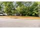Quaint light yellow home with a covered porch, framed by mature shade trees at 39 Selma Dr, Mooresville, NC 28115