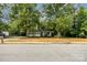 Quaint light yellow home with a covered porch, framed by mature shade trees at 39 Selma Dr, Mooresville, NC 28115