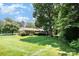 Large backyard with a well-manicured lawn, mature trees, and brick home at 400 S Westover Dr, Monroe, NC 28112