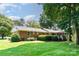 Expansive backyard featuring a brick home, lush lawn, mature trees, and a screened-in porch with deck at 400 S Westover Dr, Monroe, NC 28112