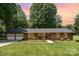 Charming brick home with an attached two-car garage, lush green lawn, and mature trees at 400 S Westover Dr, Monroe, NC 28112