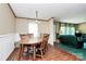 Charming dining room with a wooden table set for six, wainscoting detail, and hardwood floors, adjacent to the living area at 4104 Pebblebrook Sw Cir, Concord, NC 28027