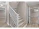 White stair case leading to an open space and doorway creates a light and airy feel, enhanced by wood floors at 5916 Cashion Rd, Huntersville, NC 28078