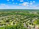 Aerial view of a neighborhood with tree-lined streets, manicured lawns, and houses, set against a bright sky with scattered clouds at 622 Lorain Nw Ave, Concord, NC 28027