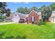Attractive home with brick and siding, a two-car garage, complemented by a lush green lawn and manicured landscaping at 7033 Spandril Ln, Charlotte, NC 28215
