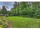 Manicured backyard featuring an expansive green lawn, mature trees and landscaped garden at 7319 Stonehaven Dr, Waxhaw, NC 28173