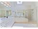Bright bathroom featuring a large soaking tub, glass shower, and double vanity with a skylight at 7319 Stonehaven Dr, Waxhaw, NC 28173