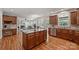 Open kitchen with wood cabinets, stainless appliances, island, and view to living room with fireplace at 7319 Stonehaven Dr, Waxhaw, NC 28173
