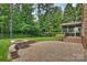 Stone patio with a fire pit, beautiful landscaping and a view of the wooded backyard at 7319 Stonehaven Dr, Waxhaw, NC 28173