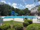 Community pool featuring a slide, chairs and manicured bushes under a partly cloudy sky at 7319 Stonehaven Dr, Waxhaw, NC 28173