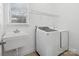 Bright laundry room featuring modern washer and dryer, utility sink, and storage shelf at 1001 Hampton Grove Rd, Waxhaw, NC 28173