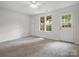 Bright bedroom featuring neutral walls, carpet, ceiling fan, two windows, and a door to outside at 1231 Maple Shade Ln, Charlotte, NC 28270