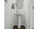 Small powder room with a sleek white pedestal sink, modern faucet, decorative mirror, and wood floors at 133 Aspire Cir, Wingate, NC 28174