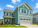 Inviting exterior featuring a two-car garage, covered porch, and light teal plank and shake siding at 133 Aspire Cir, Wingate, NC 28174
