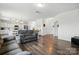 Bright, open living room with wood floors leading to a kitchen with white cabinets and modern hanging pendant lights at 133 Aspire Cir, Wingate, NC 28174
