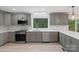 Gray kitchen with stainless appliances, tiled backsplash, and a bright window overlooking a wooded area at 136 Digh Cir # 4, Mooresville, NC 28117