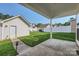 View of the backyard from a covered patio with a walkway to a detached garage and white fence at 13820 Cypress Woods Dr, Huntersville, NC 28078