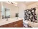 Bright bathroom featuring a double sink vanity, toilet, and shower with floral curtain at 13820 Cypress Woods Dr, Huntersville, NC 28078