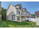 Exterior view of a multi-story house with a well-maintained lawn, covered patio, and white fence at 13820 Cypress Woods Dr, Huntersville, NC 28078