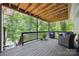 Inviting covered deck with wood ceiling, blue chairs, and scenic views of lush greenery and lake at 2004 Marquesas Ave, Tega Cay, SC 29708