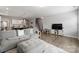 Inviting living room showcasing a gray sofa, wood floors, and an open layout leading to the kitchen and stairs at 204 Fesperman Cir, Troutman, NC 28166